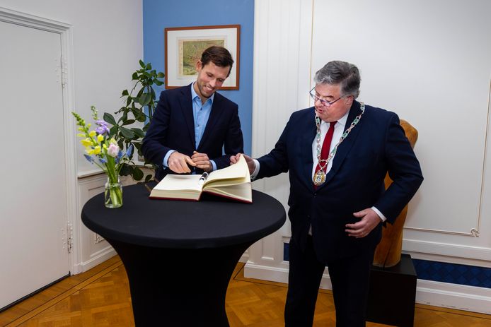 Koen Metsemakers tekent het exclusieve Nijmeegse gastenboek Het Boek van de Stad. Burgemeester Bruls bladert het boek door om te laten zien welke beroemdheden de Olympisch roeikampioen zijn voorgegaan.