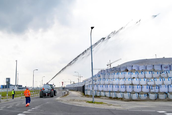 Het spuiten van een laagje cellulose op één van de zandhopen op het sluizencomplex van Terneuzen om zandverstuivingen tegen te gaan.