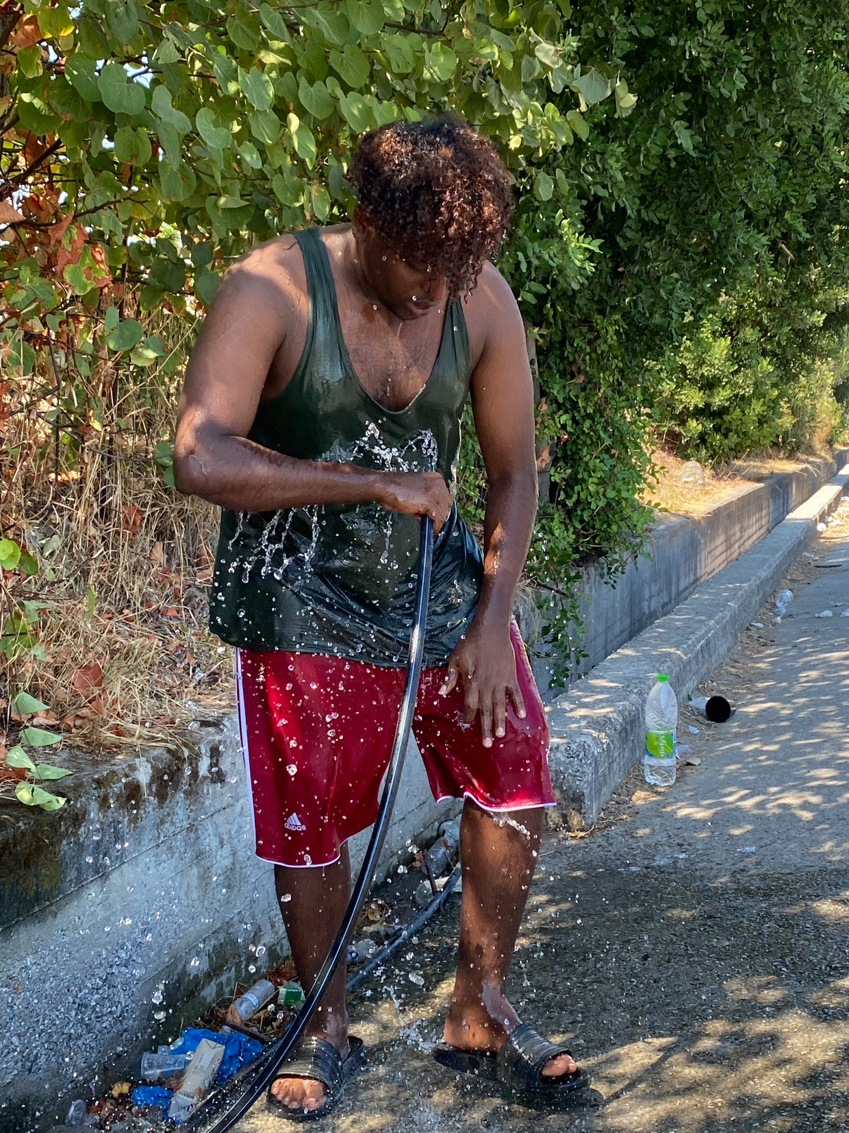 Somaliër Ukash Abdi Ali wast zich op Lesbos. Kleren houdt hij aan, want reserve  kleding heeft hij niet. Beeld Thijs Kettenis