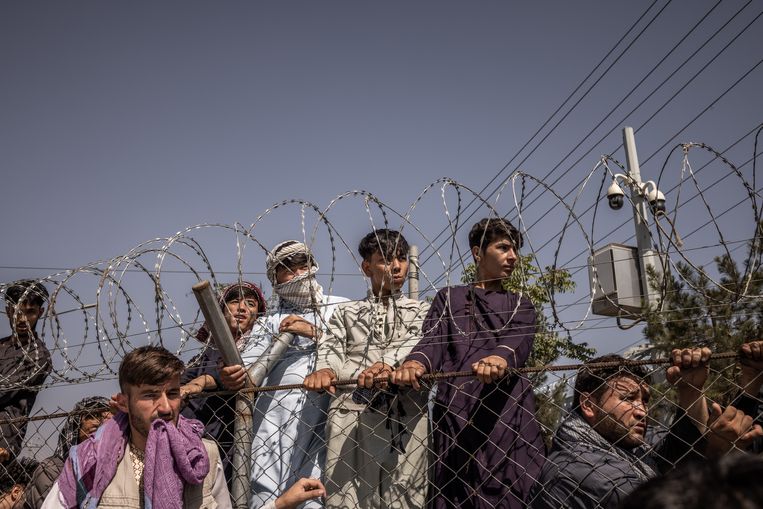 Jonge Afghanen wachten hun kans af om zich op het tarmac van de luchthaven in Kaboel te begeven. Beeld Jim Huylebroek for The New York Times