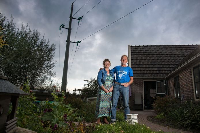 Wim en Henny Kijk in de Vegte in hun achtertuin aan de Bisschopswetering in 's-Heerenbroek. Zij hebben een 110 Kv hoogspanningsmast in hun tuin.