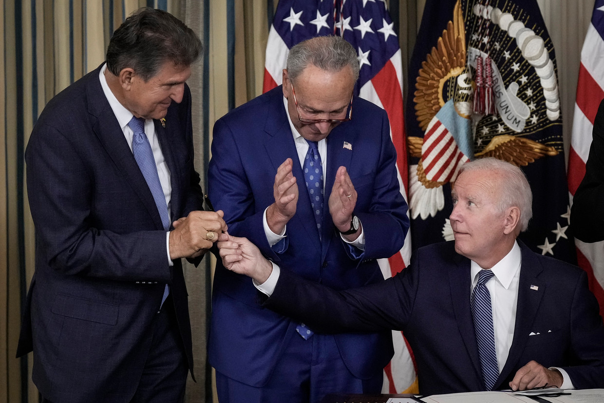 Joe Biden geeft de pen waarmee hij de Inflation Reduction Acy heeft ondertekend aan senator Joe Manchin op 16 augustus. In het midden Chuck Schumer, leider van de Democraten in de Senaat. Beeld Getty Images