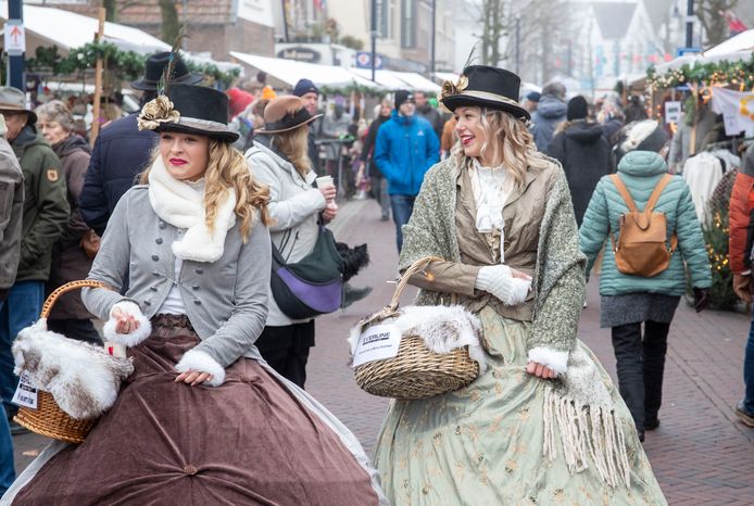 Twee in dickensiaanse outfits gehulde vrouwen delen chocolade uit op de teruggekeerde Dickens Fair in Bennekom.