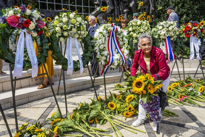 Foto ter illustratie. Genodigden leggen zonnebloemen  bij het Indisch Monument tijdens de Nationale Herdenking van het einde van de Tweede Wereldoorlog in voormalig Nederlands-Indië.