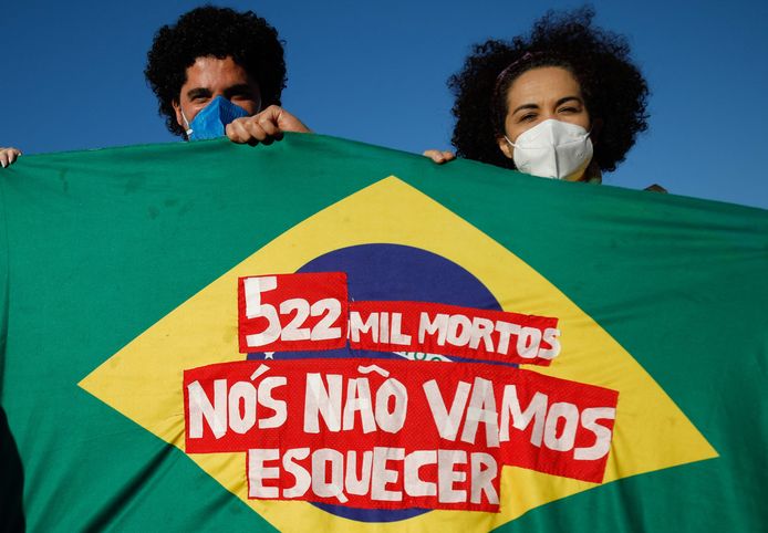 Demonstranten houden de Braziliaanse vlag vast met de tekst: "522.000 doden, wij zullen dat niet vergeten".