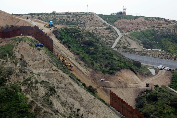 Werken aan de grensmuur tussen San Diego (rechtsboven) en Tijuana in Mexico (linksonder).