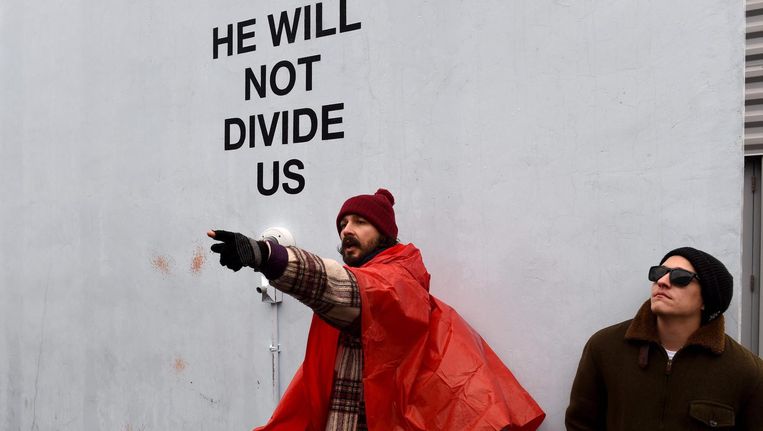 De Amerikaanse acteur Shia LaBeouf (L) bij zijn protestinstallatie 'He Will Not Divide Us'. Beeld afp
