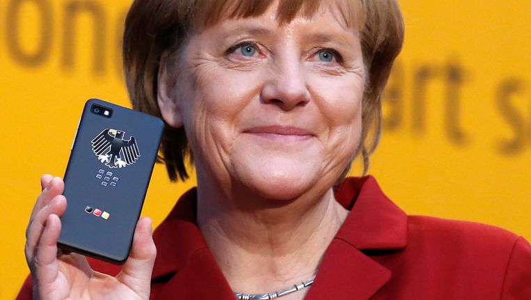 De Duitse bondskanselier Angela Merkel in maart dit jaar, toen zij nog meende dat deze extra beveiligde smartphone voor regeringsgebruik niet kon worden afgeluisterd. Beeld REUTERS