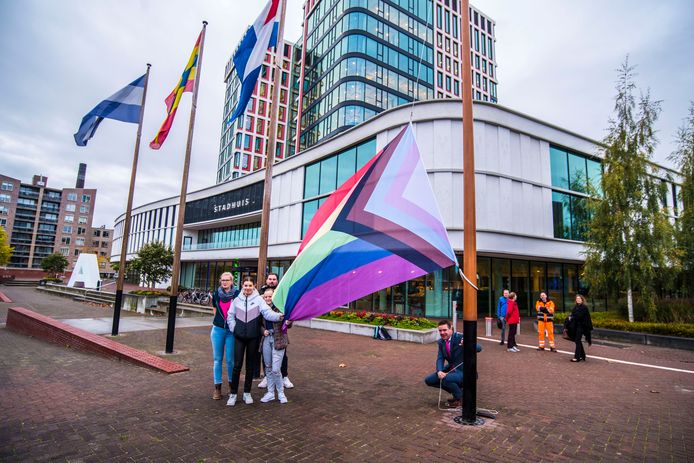 Wethouder Eugene van Mierlo (gehurkt) hijst de regenboogvlag voor het stadhuis in Almelo.