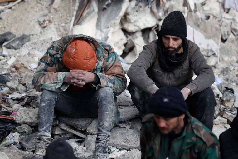 Syriërs zitten op de ruïnes van een ingestort gebouw in de stad Aleppo tijdens een poging om overlevenden onder het puin te halen.  Beeld AP