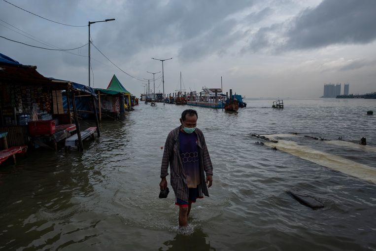 Een man waadt door het water in Jakarta. De Indonesische miljoenenstad zakte in de 20ste eeuw tussen de 2 en 3 meter. Beeld Getty Images