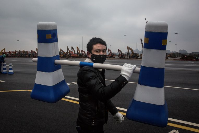 Een wegenwerker bereidt een wegblokkade voor in Wuhan. Er wordt volop gebouwd aan een nieuw prefabziekenhuis in de stad waar het virus uitbrak.  Beeld Getty Images