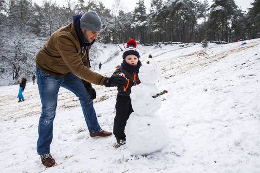 2015-01-24 12:30:24 HELLENDOORN - Een vader maakt met zijn zoontje een sneeuwpop in het bos. Grote delen van Nederland waren in de ochtend bedekt onder een pak sneeuw. ANP VINCENT JANNINK