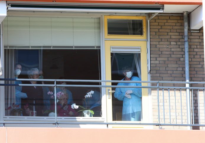 Bewoners en personeel van Huis ter Leede genieten van achter het raam van de muziek.