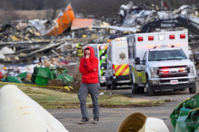 A woman walks past a line of ambulances on the site of the Mayfield, Kentucky candle factory that was destroyed by the tornado.  (Photo by John Amis / AFP)