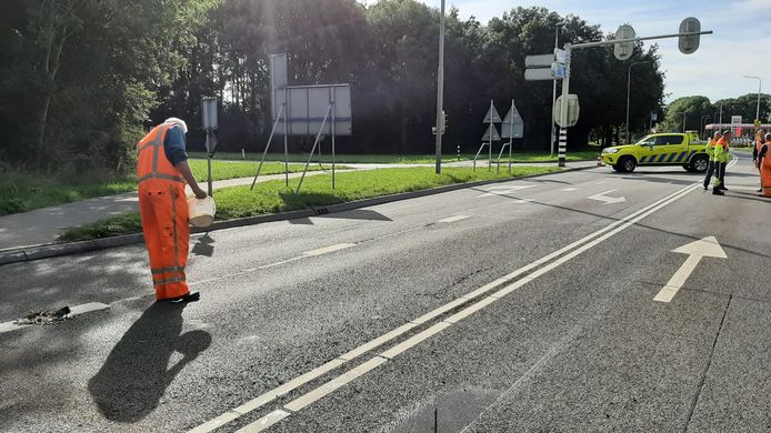 Medewerker van Rijkswaterstaat is bezig met het dichten van de gaten in het wegdek. Het landbouwvoertuig liet een spoor van vernieling achter aan én onder het viaduct over de A12.