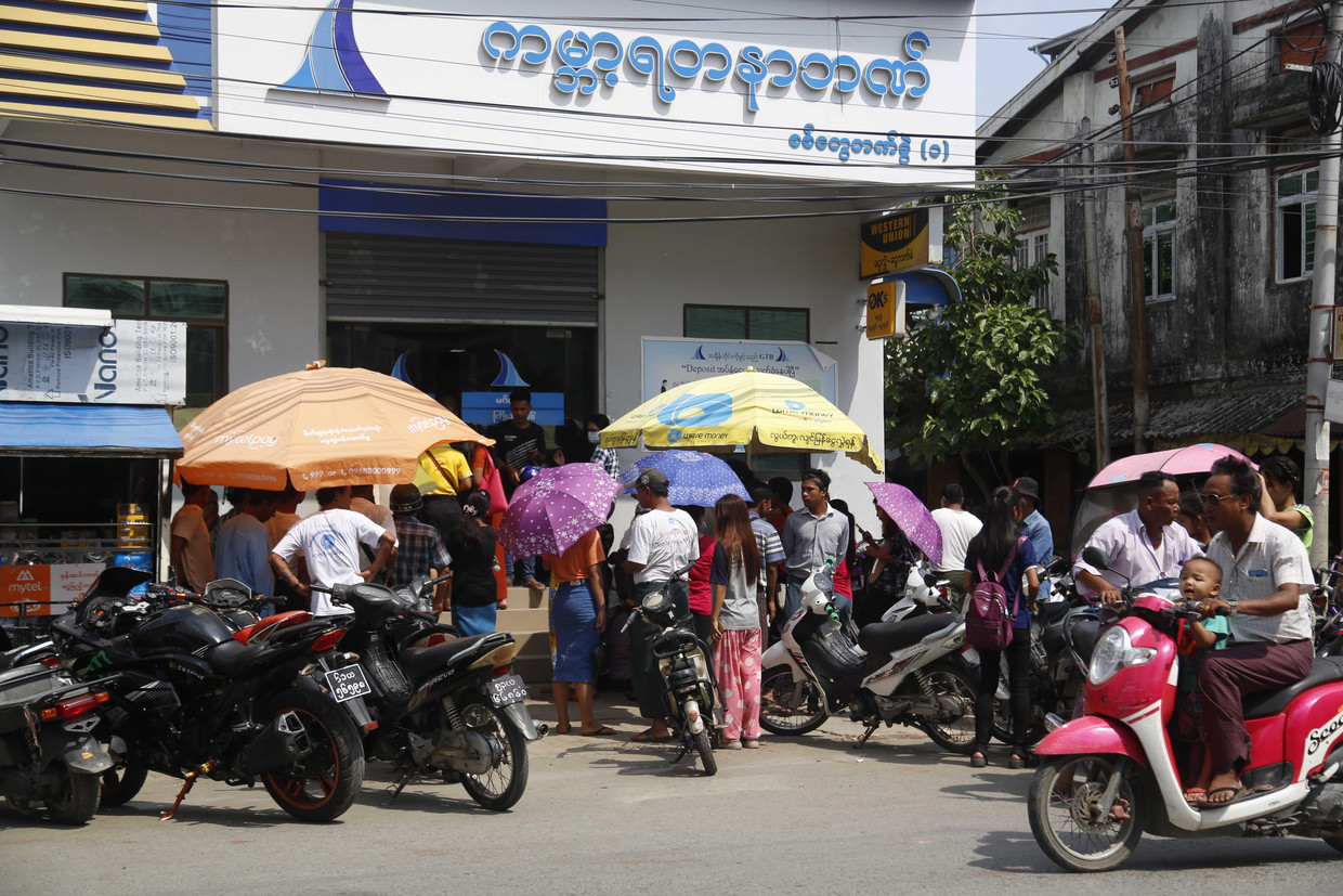 Mensen wachten bij de Global Treasure Bank in Sittwe om contant geld op kunnen nemen. Banken hebben inmiddels een tekort aan liquide middelen. Beeld EPA