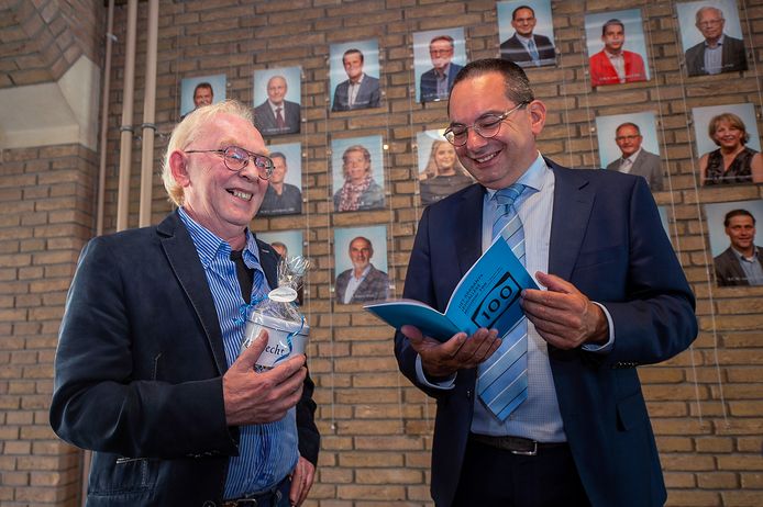 Wil de Jong, schrijver van het satirische blad 't Brabants (K)Walleke neemt met de Woensdrechtse burgemeester Steven Adriaansen, een trouw abonnee, het 100e nummer door. Op de achtergrond de raadsleden, vaak het ‘slachtoffer’ van de humoristische artikelen.