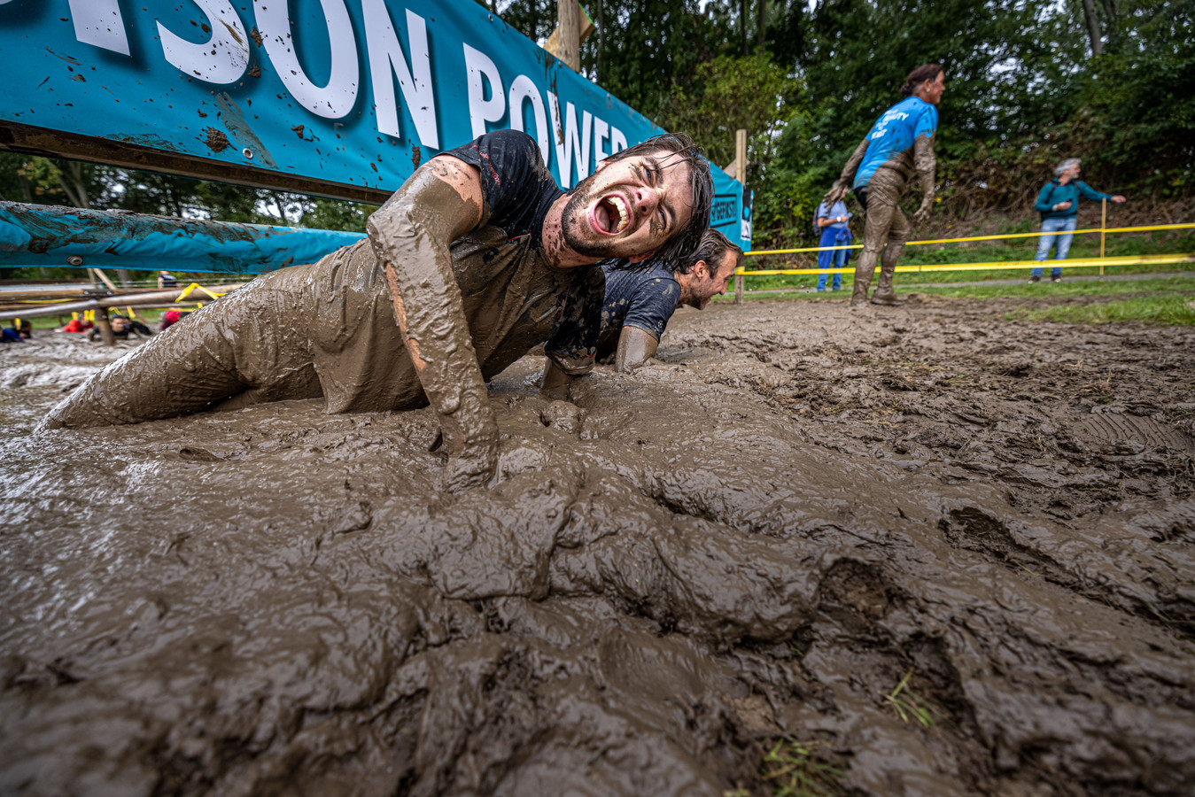 Een deelnemer aan Mud Masters in Biddinghuizen worstelt zich door de modder.