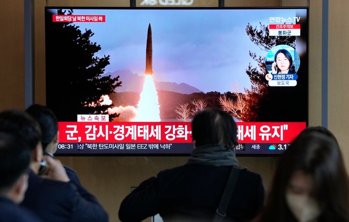Mensen kijken op een station in Seoel naar een nieuwsuitzending waarop de lancering van de raket te zien is.