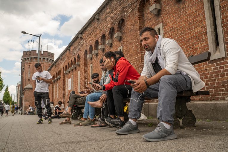 Migranten wachten voor een opvangcentrum in Brussel. Beeld Tessa Kraan