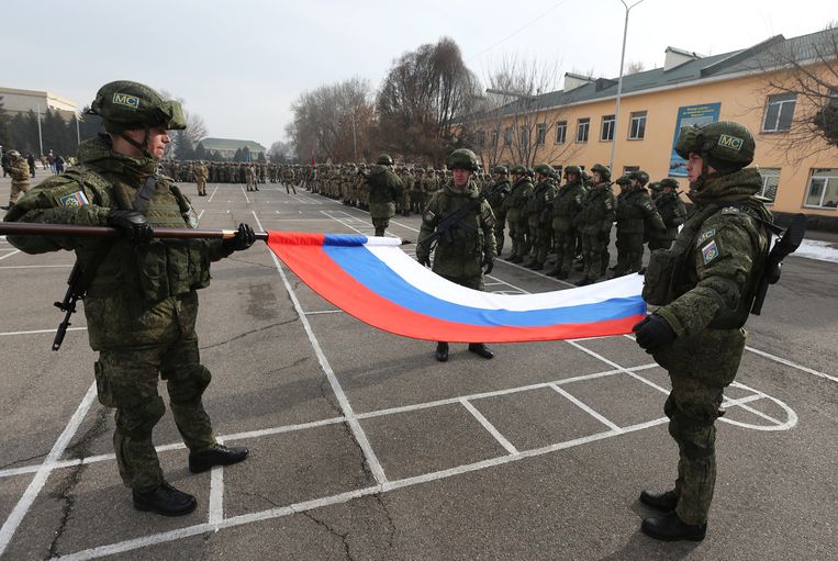 Russische militairen vouwen op het vliegveld van Almaty de nationale vlag op bij het vertrek van de eerste 'vredestroepen' uit Kazachstan.  Beeld Reuters