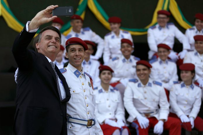 De Braziliaanse president Jair Bolsonaro maakt een selfie met studenten van een militaire academie op het hoofdkwartier van het Braziliaanse leger in de hoofdstad Brasília, tijdens een ceremonie ter gelegenheid van de Dag van de Soldaat die vrijdag in Brazilië werd gevierd.