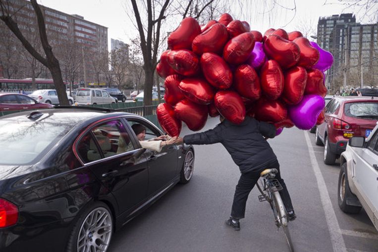 Een Chinees probeert aan automobilisten ballonnen te slijten. Beeld 