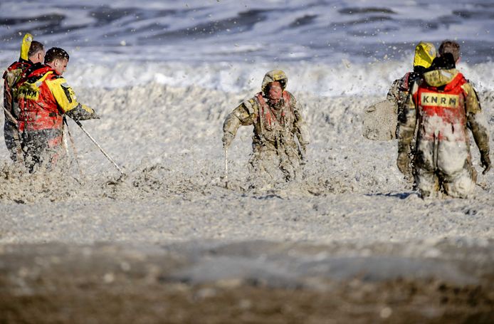 Leden van de KNRM trotseren het opvliegend schuim tijdens de hervatte zoektocht naar de vermiste watersporters bij het Noordelijk Havenhoofd. In totaal zijn er vijf mensen omgekomen.