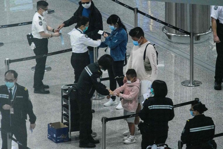 Instromende toeristen krijgen elektronische armbandjes aangemeten in de luchthaven van Hongkong. Zo houdt de overheid bij waar ze zich bevinden. Beeld AFP