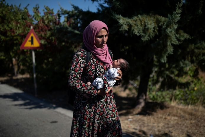 Een Syrische vrouw houdt haar tien dagen oude baby vast terwijl ze over straat wandelt op Lesbos.