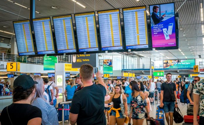 Passagiers kijken op de informatieborden op luchthaven Schiphol.