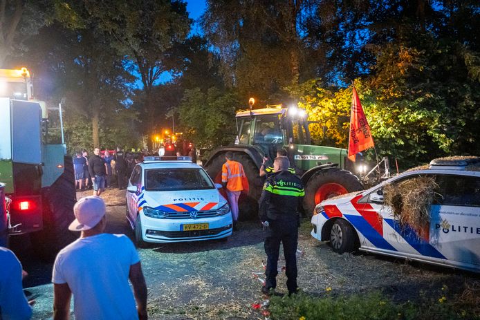 Demonstrerende boeren staan dinsdagavond bij het huis van minister Van der Wal lijnrecht tegenover de politie.