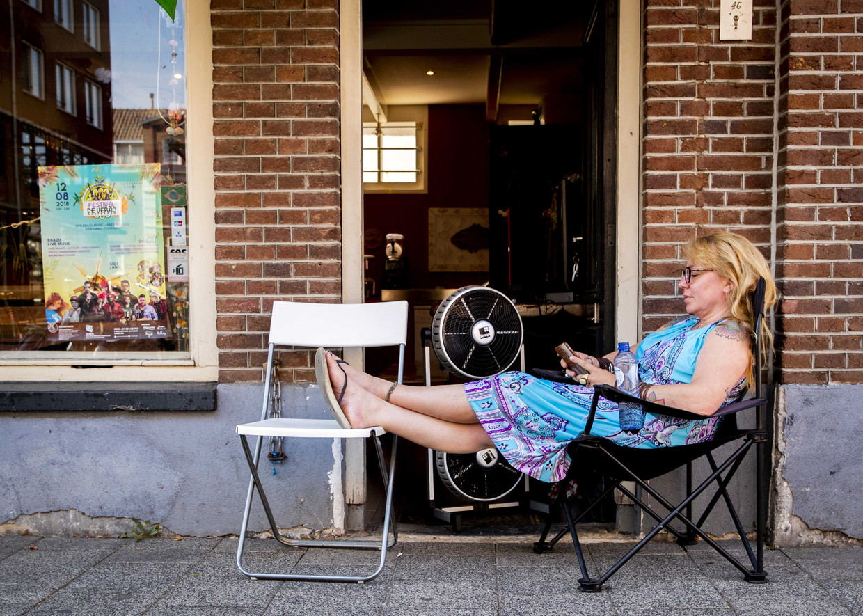 Een vrouw zoekt verkoeling voor haar winkel. Beeld ANP