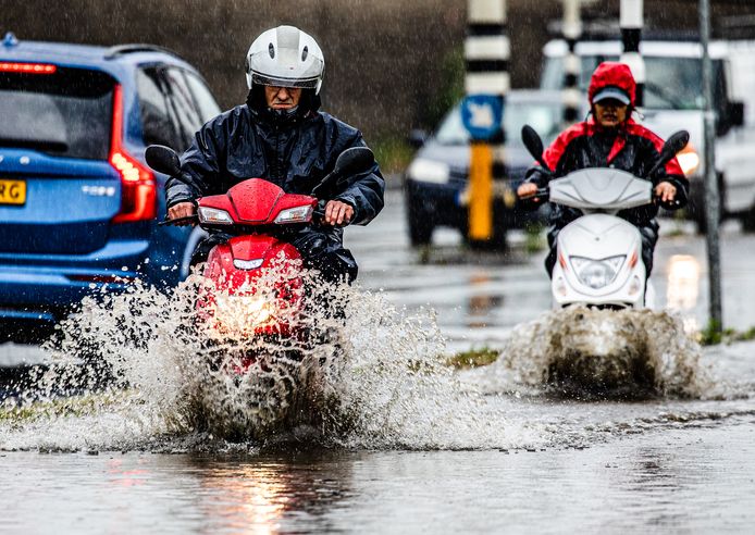 Een wolkbreuk in Dordrecht zorgt voor veel wateroverlast. Veel water op de wegen en fietspaden. Mensen banen zich een weg door de plassen.