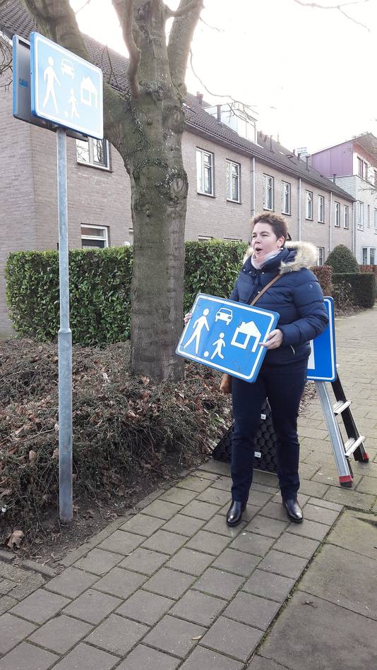 De Roosendaalse wethouder Inge Raaijmakers houdt het oude, aluminium bord vast. Het nieuwe 'refurbished sign' hangt aan de paal.