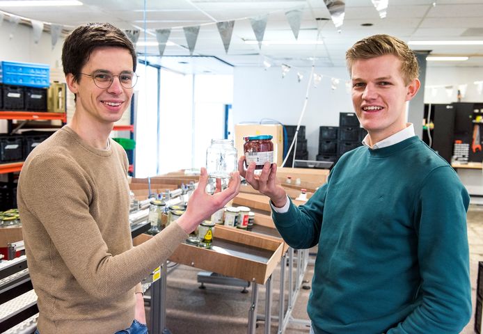 Peter Verweij en Thijs Wester met in hun handen een schoongemaakt glazen potje en een potje dat nog vies is.