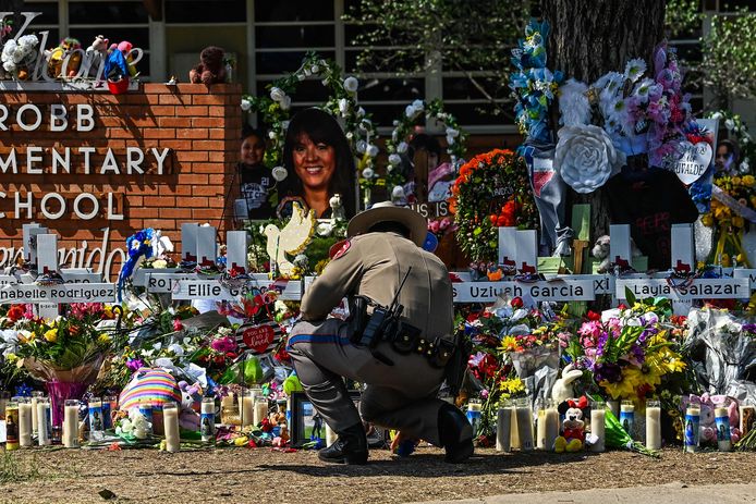 Een politieagent knielt bij de herdenkingsplaats voor de slachtoffers van de dodelijke schietpartij op de school in Uvalde (Texas).