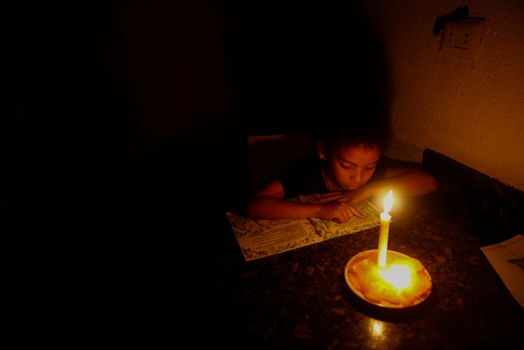 Een meisje leest met behulp van kaarslicht tijdens de stroomstoring in Caracas, Venezuela. Beeld Getty Images