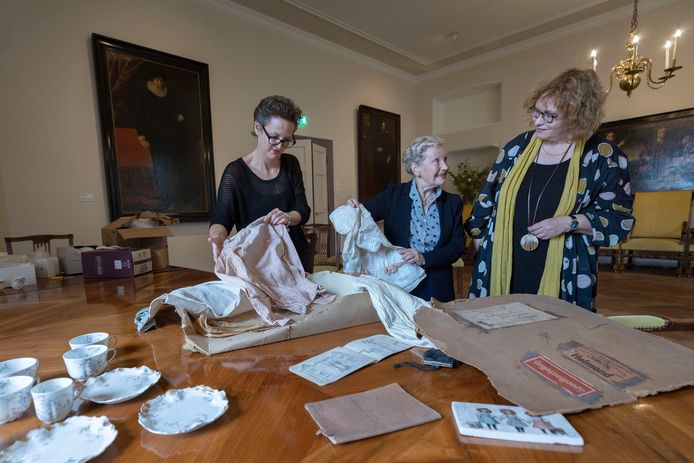 Junior conservator Mariëlle van de Kerkhof van Museum Helmond (links) kijkt wat Elisabeth de Jong van Beek en Donk en haar nichtje Emilie Lindenbergh (rechts) hebben meegebracht voor de expositie over de Helmondse jonkvrouw Emelie Wesselman.