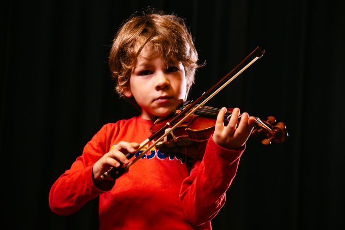 Een jongetje speelt op een viool.