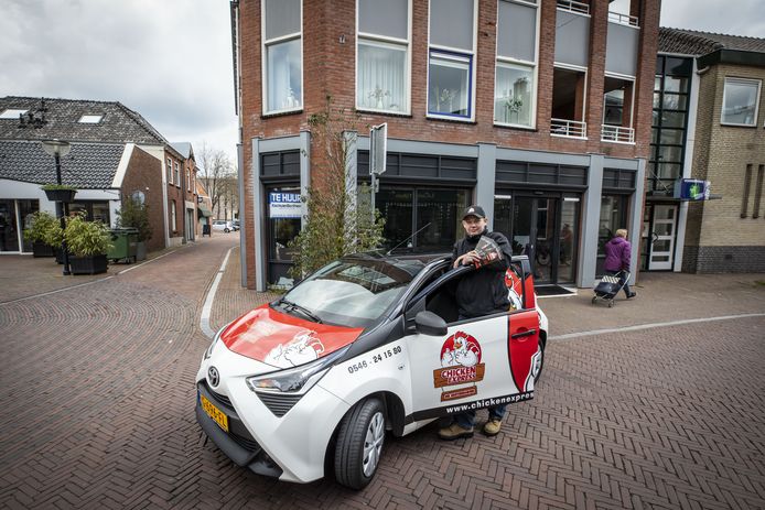 Medewerker van Chicken Express bij de bezorgauto.