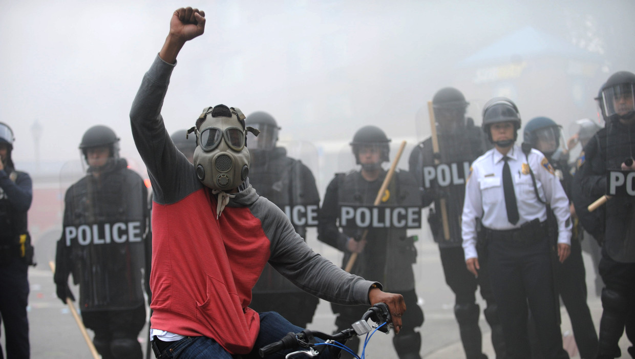 Een demonstrant bij een linie van de oproerpolitie in de Amerikaanse stad Baltimore, na de begrafenis van Freddie Gray die dodelijk gewond raakte bij zijn arrestatie. Beeld AP