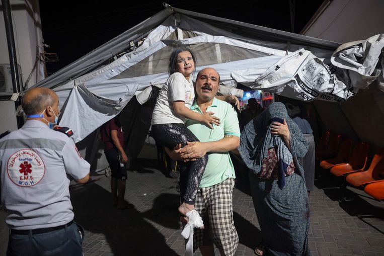Palestijnen brengen een gewond meisje naar het ziekenhuis na een luchtaanval. Beeld AFP