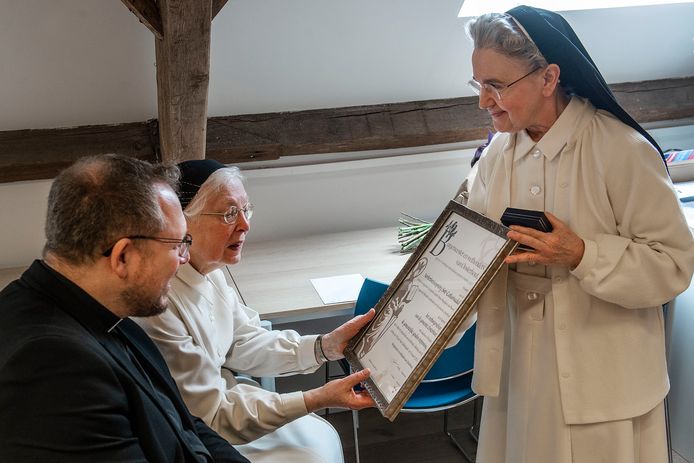 Priorin zr. Maria Magdalena laat een mede-zuster de oorkonde zien die hoort bij het ereburgerschap.