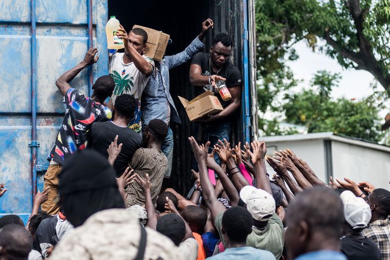 Mannen delen voedsel uit in Les Cayes, dat zwaar getroffen werd door de aardbeving vorige week zaterdag in Haïti. Beeld AFP