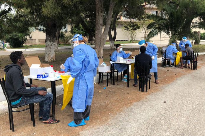 Migranten worden door Griekse gezondheidswerkers getest op het coronavirus.
