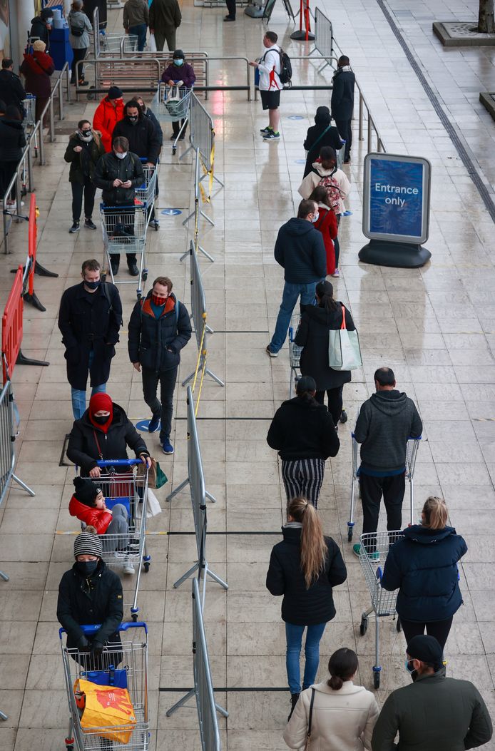 Les gens font la queue devant un magasin Tesco alors que de nouvelles restrictions sont entrées en vigueur, à Londres, en Grande-Bretagne.
