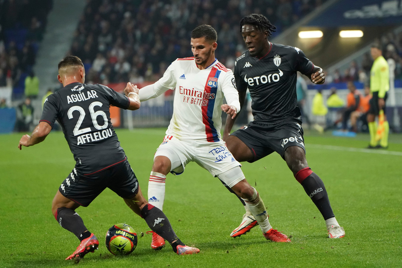 Houssem Aouar (m) namens Lyon in duel met Ruben Aguilar (l) en Axel Disasi.