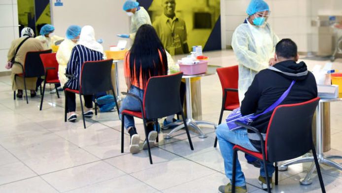 Medewerkers van de gezondheidsdienst in Dubai testen de passagiers in een zone aan de check-in.